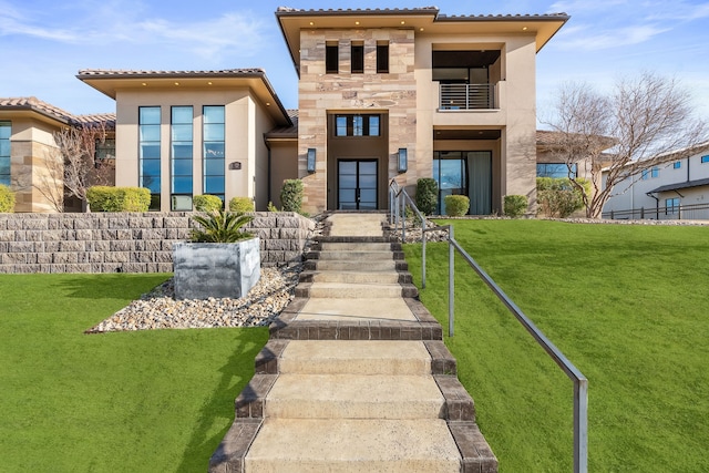 view of front of property with french doors, a front yard, and a balcony