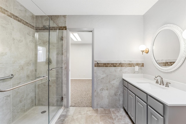 bathroom with a textured ceiling, vanity, tile walls, tile patterned floors, and a stall shower