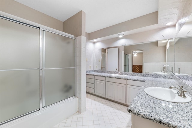 full bathroom featuring double vanity, combined bath / shower with glass door, a sink, and tile patterned floors