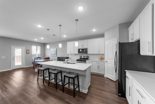 kitchen with a breakfast bar area, white cabinetry, a center island with sink, pendant lighting, and stainless steel appliances