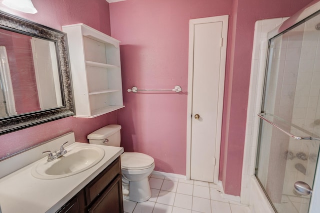 bathroom featuring baseboards, toilet, tile patterned flooring, combined bath / shower with glass door, and vanity