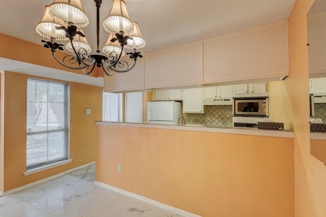 kitchen with a notable chandelier, marble finish floor, light countertops, freestanding refrigerator, and stainless steel microwave