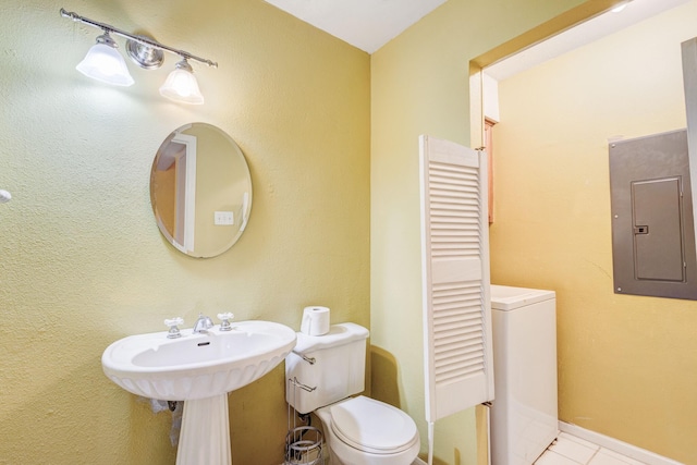 bathroom with tile patterned flooring, toilet, baseboards, electric panel, and washer / clothes dryer