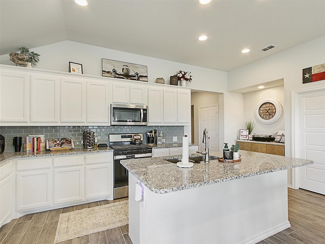 kitchen with stainless steel appliances, a kitchen island with sink, sink, and white cabinets