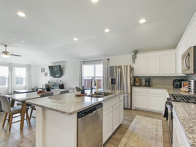 kitchen with white cabinetry, sink, stainless steel appliances, and a center island with sink