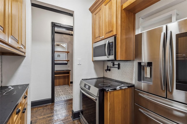 kitchen with appliances with stainless steel finishes, dark stone countertops, dark hardwood / wood-style flooring, and decorative backsplash