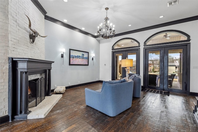 living room featuring french doors, a chandelier, ornamental molding, dark hardwood / wood-style flooring, and a fireplace