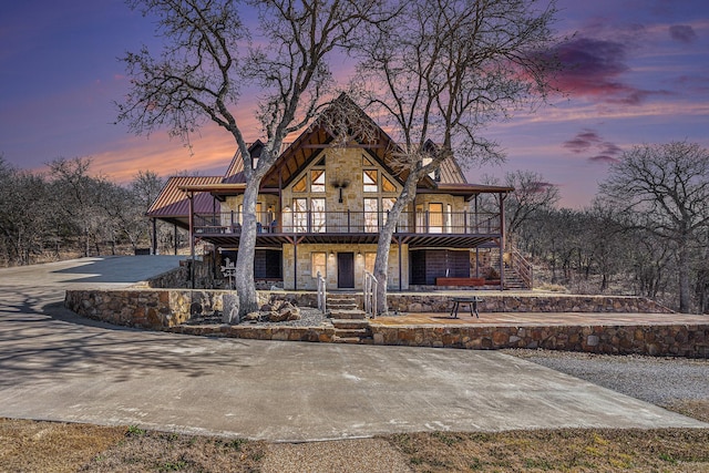 view of front of home with stone siding, concrete driveway, and stairs