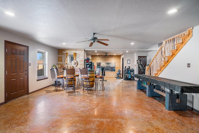 interior space with finished concrete floors, stairway, a textured ceiling, and recessed lighting