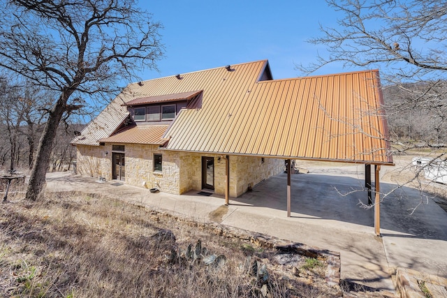 back of property featuring metal roof and stone siding