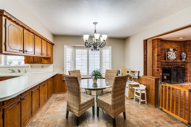 dining space featuring a textured ceiling, a brick fireplace, and a notable chandelier