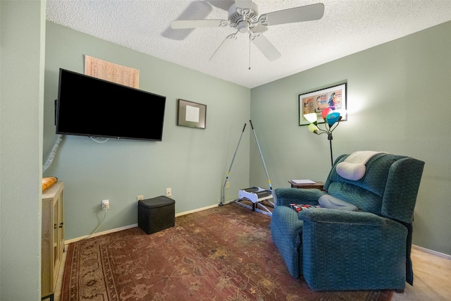 living area with ceiling fan and a textured ceiling