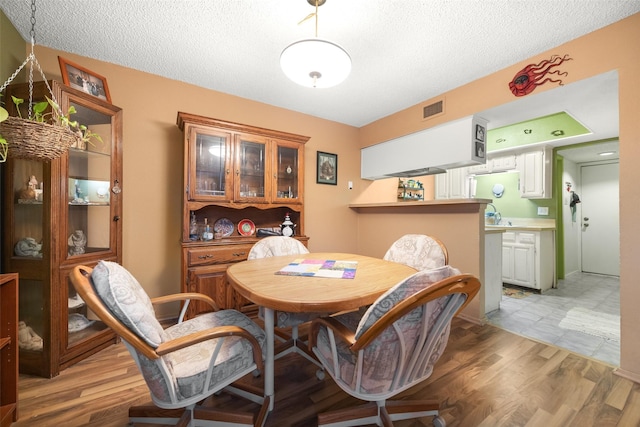 dining room featuring hardwood / wood-style flooring and a textured ceiling