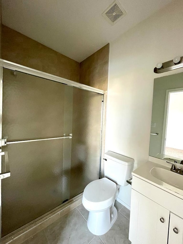 bathroom featuring vanity, toilet, tile patterned flooring, and a shower with door