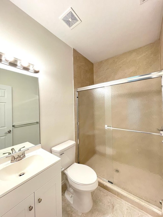 bathroom with vanity, tile patterned flooring, a shower with door, and toilet