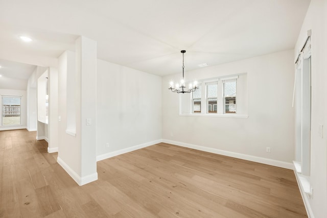 unfurnished dining area with a chandelier and light hardwood / wood-style flooring