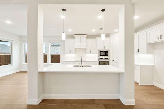 kitchen with hanging light fixtures, sink, and white cabinets