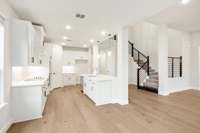 kitchen with sink, dishwasher, an island with sink, white cabinets, and black electric cooktop