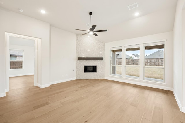 unfurnished living room featuring ceiling fan, a fireplace, light hardwood / wood-style floors, and vaulted ceiling