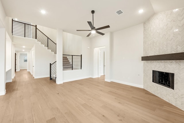 unfurnished living room featuring ceiling fan, light wood-type flooring, and a fireplace