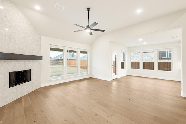 unfurnished living room with lofted ceiling, a fireplace, ceiling fan, and light wood-type flooring