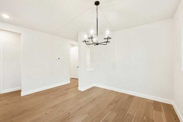 unfurnished dining area with a chandelier and light hardwood / wood-style flooring