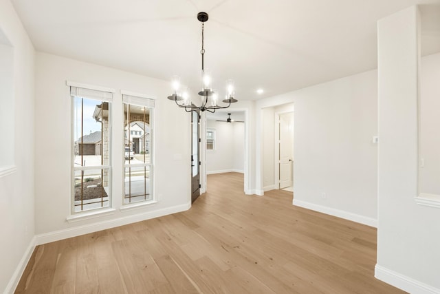 unfurnished dining area with an inviting chandelier and light hardwood / wood-style floors