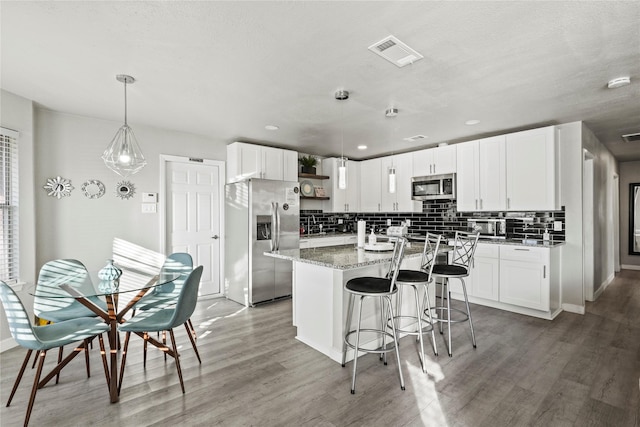 kitchen with appliances with stainless steel finishes, a center island, pendant lighting, and white cabinets