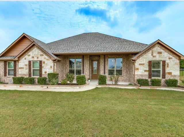view of front of property featuring stone siding, a shingled roof, and a front yard