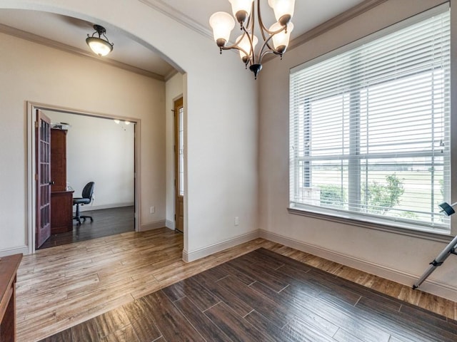 spare room featuring an inviting chandelier, crown molding, and wood-type flooring