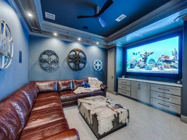 home theater featuring ceiling fan, ornamental molding, a raised ceiling, and light carpet