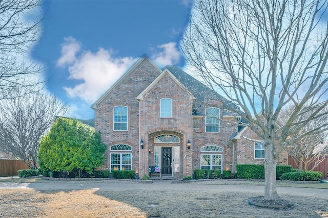 view of front facade featuring brick siding and fence