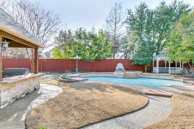 view of pool featuring a fenced backyard, an outdoor kitchen, a gazebo, and grilling area