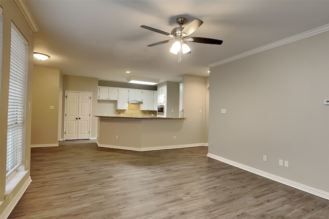 unfurnished living room featuring dark wood-type flooring, ornamental molding, and ceiling fan