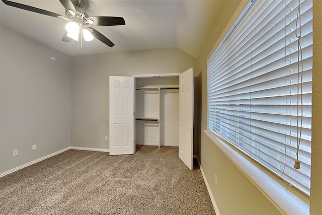 unfurnished bedroom with vaulted ceiling, light colored carpet, a closet, and ceiling fan