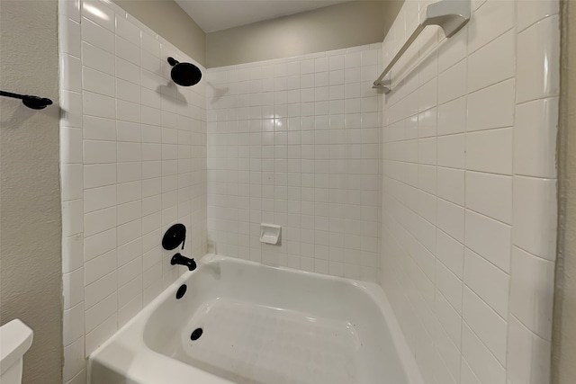 bathroom featuring toilet and tiled shower / bath