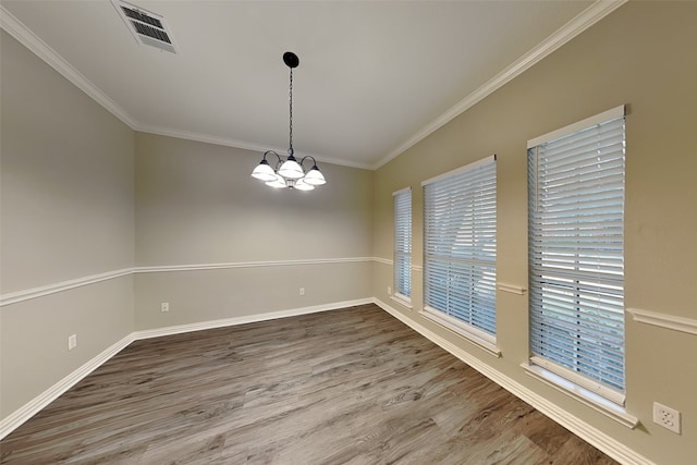 spare room featuring an inviting chandelier, hardwood / wood-style floors, and ornamental molding