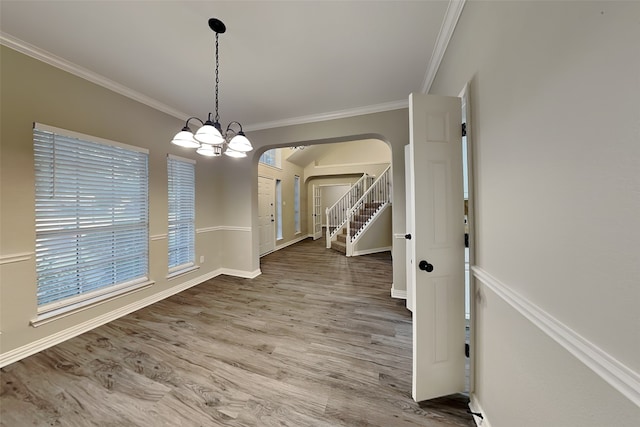 unfurnished dining area featuring crown molding, wood-type flooring, and a chandelier