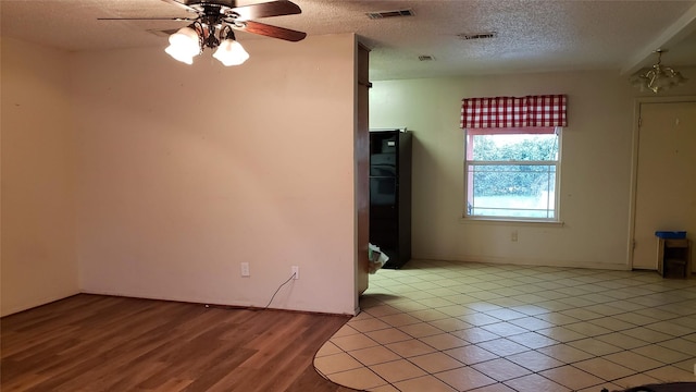 spare room featuring ceiling fan, light hardwood / wood-style floors, and a textured ceiling