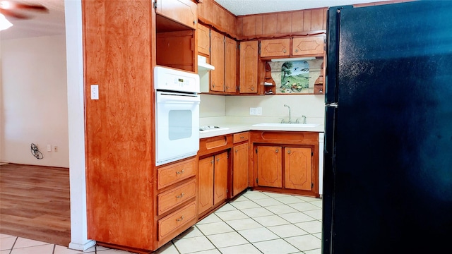 1802 SE 26th Ave, Mineral Wells, TX 76067 - kitchen featuring freestanding refrigerator, white oven, light countertops, under cabinet range hood, and a sink