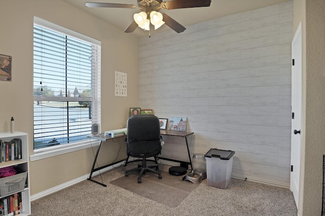 office area featuring light carpet, ceiling fan, and wood walls