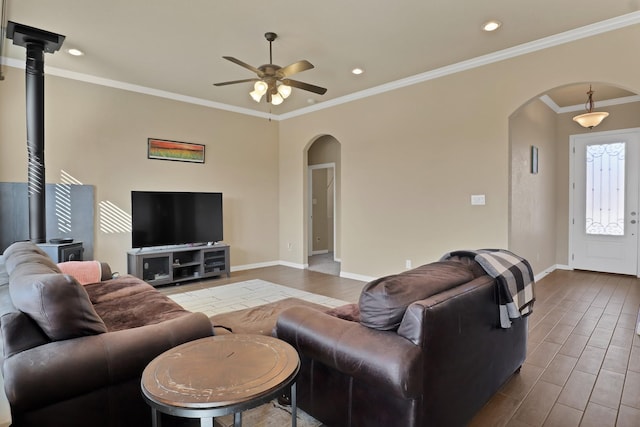 living room with hardwood / wood-style flooring, ornamental molding, ceiling fan, and a wood stove