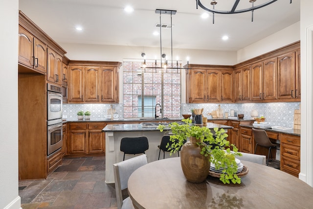 kitchen featuring sink, tasteful backsplash, double oven, a kitchen island, and pendant lighting