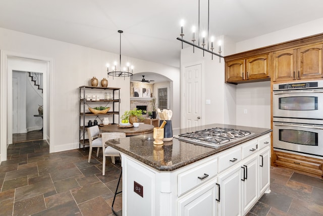 kitchen featuring appliances with stainless steel finishes, dark stone countertops, hanging light fixtures, a center island, and white cabinets