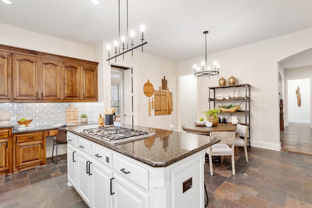 kitchen featuring decorative light fixtures, white cabinetry, decorative backsplash, a center island, and stainless steel gas cooktop