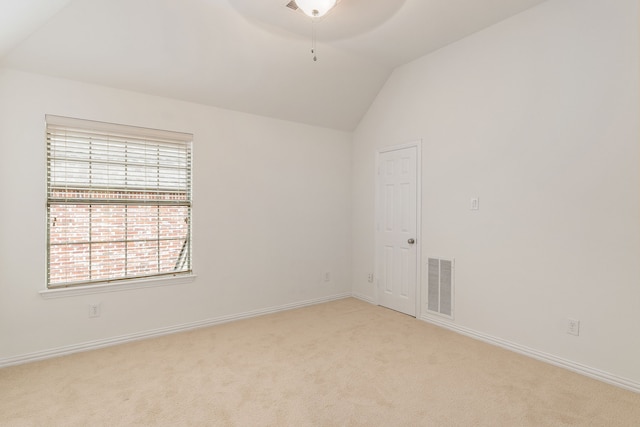 spare room featuring light colored carpet and lofted ceiling