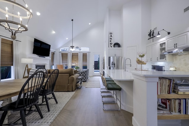 kitchen featuring white cabinetry, hanging light fixtures, stainless steel fridge, and a kitchen breakfast bar