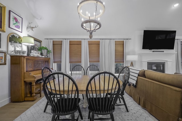 dining area with light wood-type flooring, vaulted ceiling, and a notable chandelier