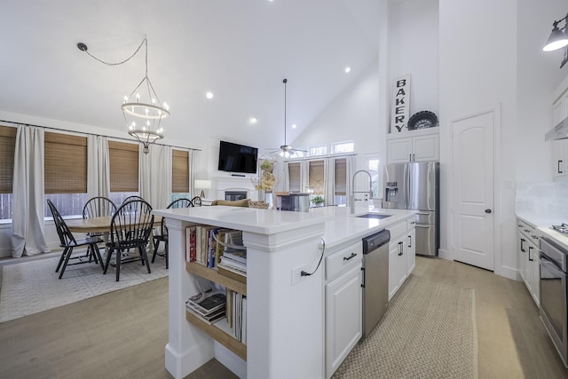 kitchen with white cabinetry, appliances with stainless steel finishes, sink, and a center island with sink