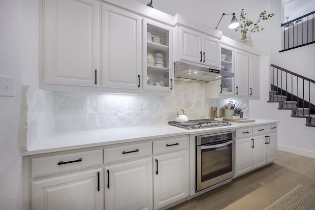 kitchen featuring tasteful backsplash, stainless steel appliances, light wood-type flooring, and white cabinets